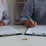 Faceless couple signing agreements with rings on the table - separation agreement without a lawyer - Kelly Jordan Family Law.