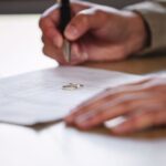 Faceless man writing on paper with a ring - do you need a lawyer for divorce - Kelly Jordan Family Law.
