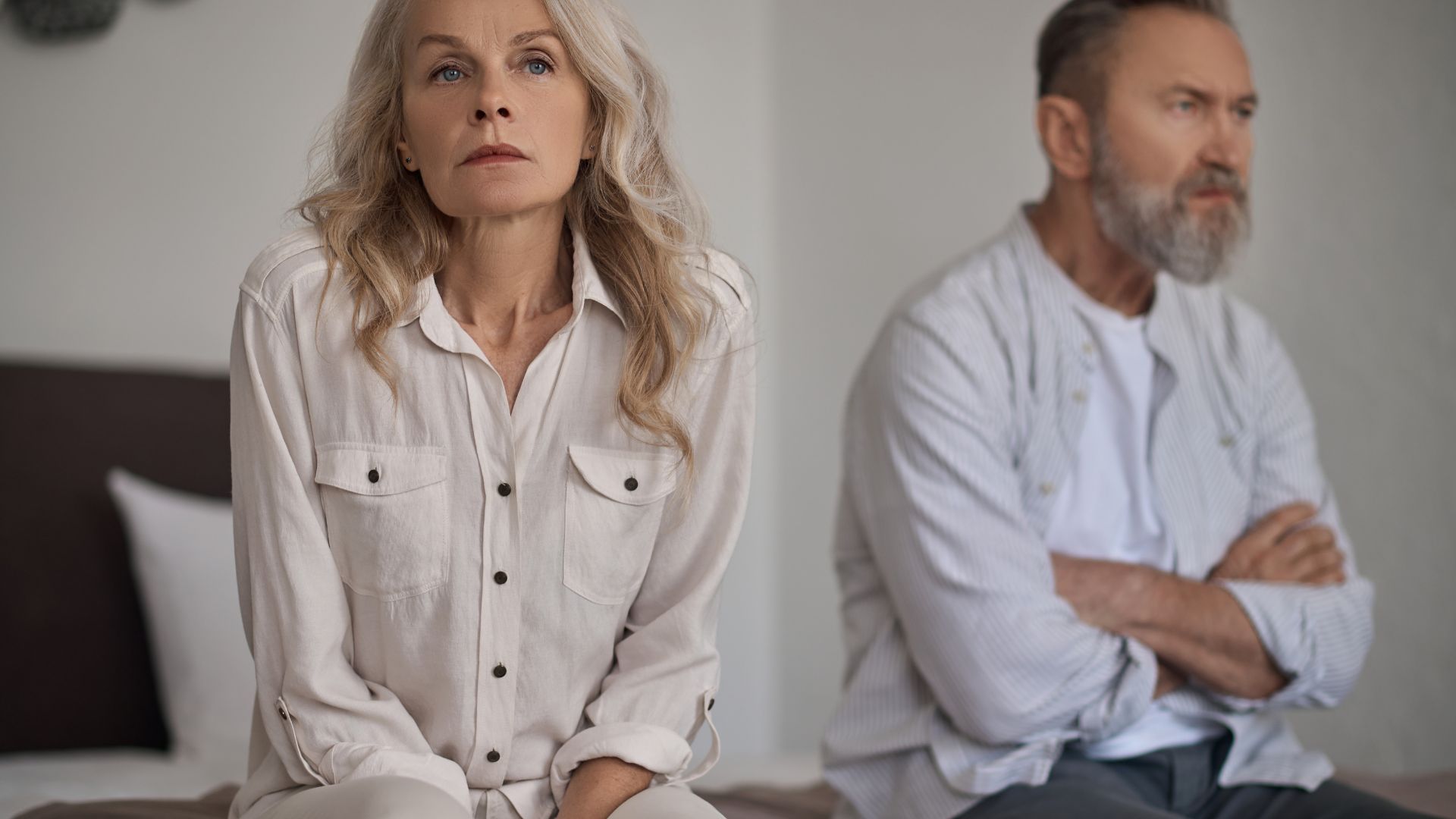 Couple, sitting on a bed unhappy - high net worth divorce insights from Kelly Jordan Family Law.